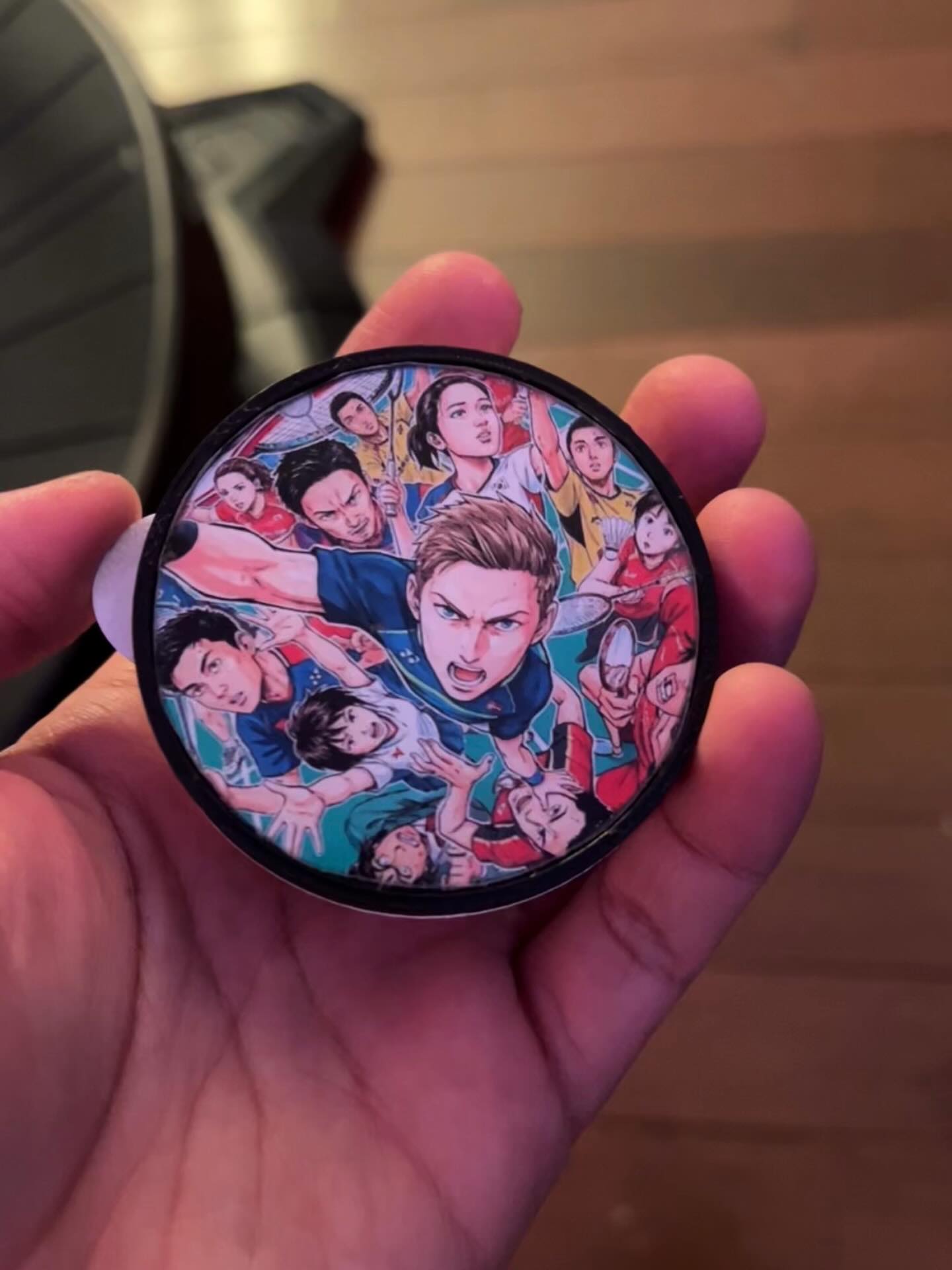 Custom 3D-printed badminton tube cap with anime design held in hand